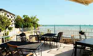 Ulkoravintola, josta on näkymä merenrannalle ja rannikkomaisemaan. (Tekoälyn luoma teksti)