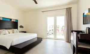 Hotellihuone, jossa on parivuode, kirjoituspöytä ja parvekkeen ovet. (Tekoälyn luoma teksti)