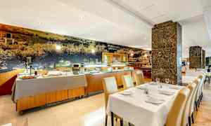 Ravintolan sisustus, jossa katetut pöydät ja taustalla seisova buffet-pöytä. (Tekoälyn luoma teksti)