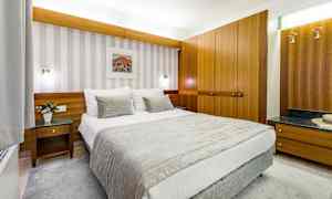 Hotellihuone, jossa on pedattu sänky, puusisustus ja seinätaidetta. (Tekoälyn luoma teksti)