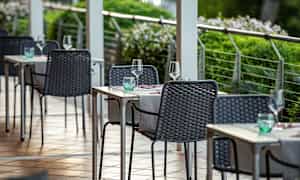 Ulkoilmaravintolan terassi, jossa pöydät ja tuolit katettu laseilla ja servieteillä. (Tekoälyn luoma teksti)