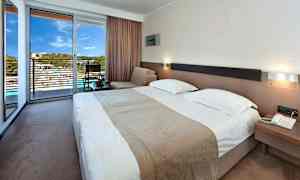 Hotellihuone, jossa on parivuode, oleskelutila ja terassi näkymällä. (Tekoälyn luoma teksti)