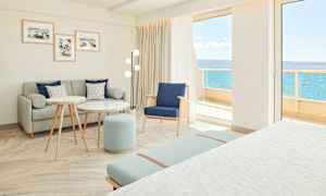 Valoisa ja moderni hotellihuone, jossa istuinryhmä ja merinäköala. (Tekoälyn luoma teksti)