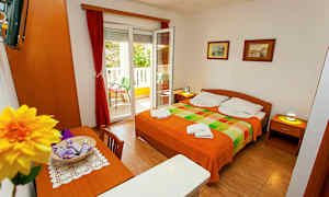 Huone, jossa on parivuode, pöytä, tuolit ja avoin parvekkeen ovi. (Tekoälyn luoma teksti)