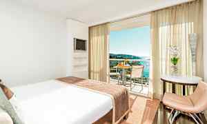 Hotellihuone, jossa on suuri sänky ja parveke merelle päin. (Tekoälyn luoma teksti)