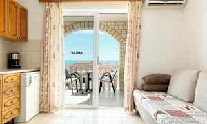 Olohuone, jossa vuodesohva, keittiö ja parveke, jolta on näkymä merelle. (Tekoälyn luoma teksti)