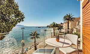 Näkymä parvekkeelta aurinkoiselle rannalle, jossa on palmuja ja kirkasta vettä. (Tekoälyn luoma teksti)