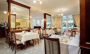 Ravintola, jossa on katetut pöydät ja tuolit sisätiloissa. (Tekoälyn luoma teksti)