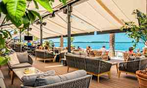 Ulkoterassi pöytineen ja sohvineen, taustalla näkymä merelle. (Tekoälyn luoma teksti)