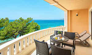 Parveke, jolta on näkymä merelle, istuinryhmä ja kaksi aurinkotuolia. (Tekoälyn luoma teksti)