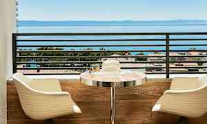 Näkymä merelle parvekkeelta, jossa istuimia ja pöytä. (Tekoälyn luoma teksti)