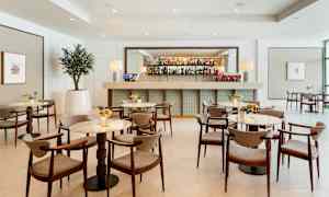 Moderni baari, jossa on tyylikkäitä pöytiä ja tuoleja vaaleassa sisustuksessa. (Tekoälyn luoma teksti)