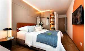 Moderni hotellihuone, jossa parivuode, koristeelliset tyynyt ja valaistus. (Tekoälyn luoma teksti)