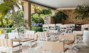 Ulkoterassi, jossa pöytiä, tuoleja ja kivimuuri. (Tekoälyn luoma teksti)