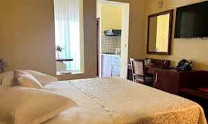 Kuva hotellihuoneesta, jossa on parivuode, työpöytä ja keittokomero. (Tekoälyn luoma teksti)