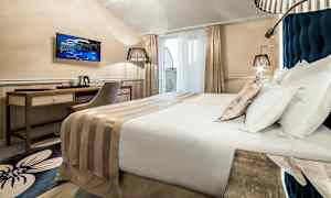 Moderni hotellihuone, jossa parivuode, työpöytä, tuoli ja televisio. (Tekoälyn luoma teksti)