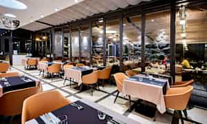 Ravintola moderneilla sisustuksilla ja suurilla lasiosuuksilla. (Tekoälyn luoma teksti)