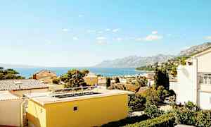 Näkymä kattotasanteiden yli, taustalla meri ja vuoret. (Tekoälyn luoma teksti)