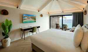 Hotellihuone, jossa on parisänky, työpöytä, televisio ja parveke merinäköalalla. (Tekoälyn luoma teksti)