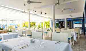 Terassi, jolla pöydät on katettu valkoisilla pöytäliinoilla. (Tekoälyn luoma teksti)