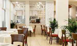 Ravintola, jossa on pöytiä ja tuoleja, koristeltu kasveilla ja lasiseinä puumuotoilulla. (Tekoälyn luoma teksti)