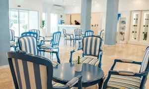 Valoisa ja avara hotelliaula, jossa on sinivalkoraitaisia istuimia ja pyöreä pöytä. (Tekoälyn luoma teksti)