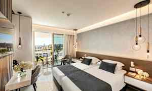 Modernisti sisustettu hotellihuone, jossa on parivuode, istumapaikkoja ja parveke näkymällä. (Tekoälyn luoma teksti)