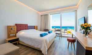 Hotellihuone, jossa on parivuode, istuinryhmä ja näkymä merelle. (Tekoälyn luoma teksti)