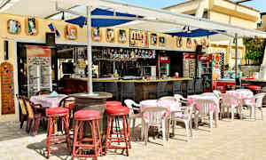 Ulkoravintola, jossa on pöytiä, tuoleja ja baari. (Tekoälyn luoma teksti)