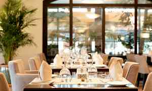 Ravintolapöytä tyylikkäästi katettuna, sisältäen lasit, lautaset ja taitellut lautasliinat. (Tekoälyn luoma teksti)