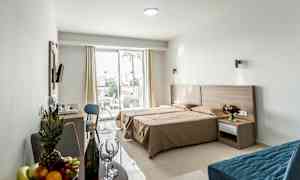 Hotellihuone, jossa on parivuode, istuinalue ja ulkoterassi. (Tekoälyn luoma teksti)