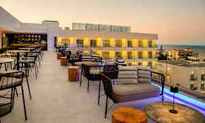 Kattoterassi istumapaikoilla ja näkymä merelle sekä hotellirakennuksiin. (Tekoälyn luoma teksti)