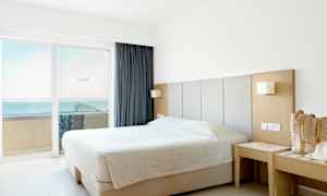 Hotellihuone, jossa parivuode lähellä ikkunaa, josta näkymät merelle. (Tekoälyn luoma teksti)