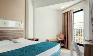 Hotellihuone, jossa pedattu sänky, yöpöytä ja parvekkeen ovi. (Tekoälyn luoma teksti)