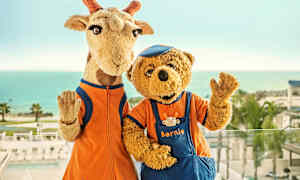 Kaksi maskottia, kirahvi ja karhu, seisovat meren edessä taustalla. (Tekoälyn luoma teksti)