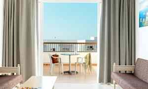 Hotellihuone, josta on näkymä parvekkeelle, jossa on pöytä ja tuolit. (Tekoälyn luoma teksti)