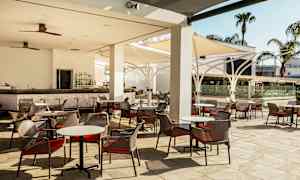 Kuva ulkoterassista, jossa on pöytiä ja tuoleja sekä baari. (Tekoälyn luoma teksti)