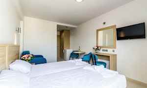 Hotellihuone, jossa sänky, pöytä, tuoli, peili ja televisio. (Tekoälyn luoma teksti)