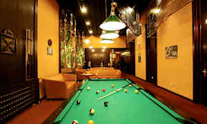 Pelitila, jossa biljardipöytä, sohvat ja taiteellinen sisustus. (Tekoälyn luoma teksti)