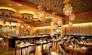 Ravintola, jossa on modernit huonekalut ja koristeelliset valaisimet katossa. (Tekoälyn luoma teksti)