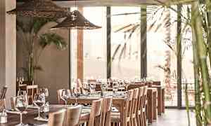 Ravintolan sisustus, jossa on puupöytiä, tuoleja ja koristeltu laseilla ja aterimilla. (Tekoälyn luoma teksti)