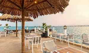 Ulkoruokailutila aurinkovarjoilla lähellä merta. (Tekoälyn luoma teksti)