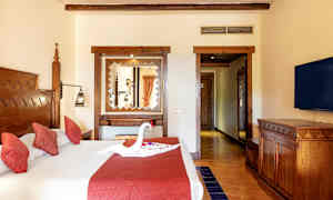 Hotellihuone, jossa parivuode, punaiset tyynyt ja sängyllä koriste, joka on muotoiltu joutseneksi. (Tekoälyn luoma teksti)