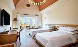 Hotellihuone, jossa on kaksi erillistä vuodetta, kirjoituspöytä ja oleskelutila parvekkeen vieressä. (Tekoälyn luoma teksti)