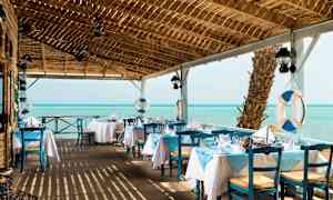 Ravintola, jossa on sinisiä ja valkoisia värejä meren äärellä. (Tekoälyn luoma teksti)