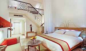 Modernisti sisustettu hotellisviitti, jossa on parivuode, istuinryhmä ja portaat avotilaan. (Tekoälyn luoma teksti)