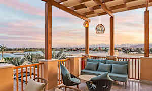 Terassi, jolla on sohvaryhmä ja näkymä kanaaliin ja rakennuksiin auringonlaskussa. (Tekoälyn luoma teksti)