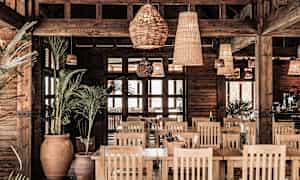 Ravintolan sisustus, jossa on puuyksityiskohtia, kasveja ja rottinkivalaisimia. (Tekoälyn luoma teksti)