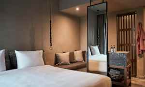 Makuuhuoneessa on suuri sänky, tyynyjä, sohva ja korkea peili. (Tekoälyn luoma teksti)