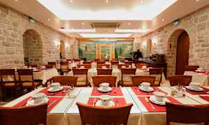 Ruokasali katetuilla pöydillä ja tuoleilla, jota ympäröivät kiviseinät ja koristaa seinämaalaus. (Tekoälyn luoma teksti)